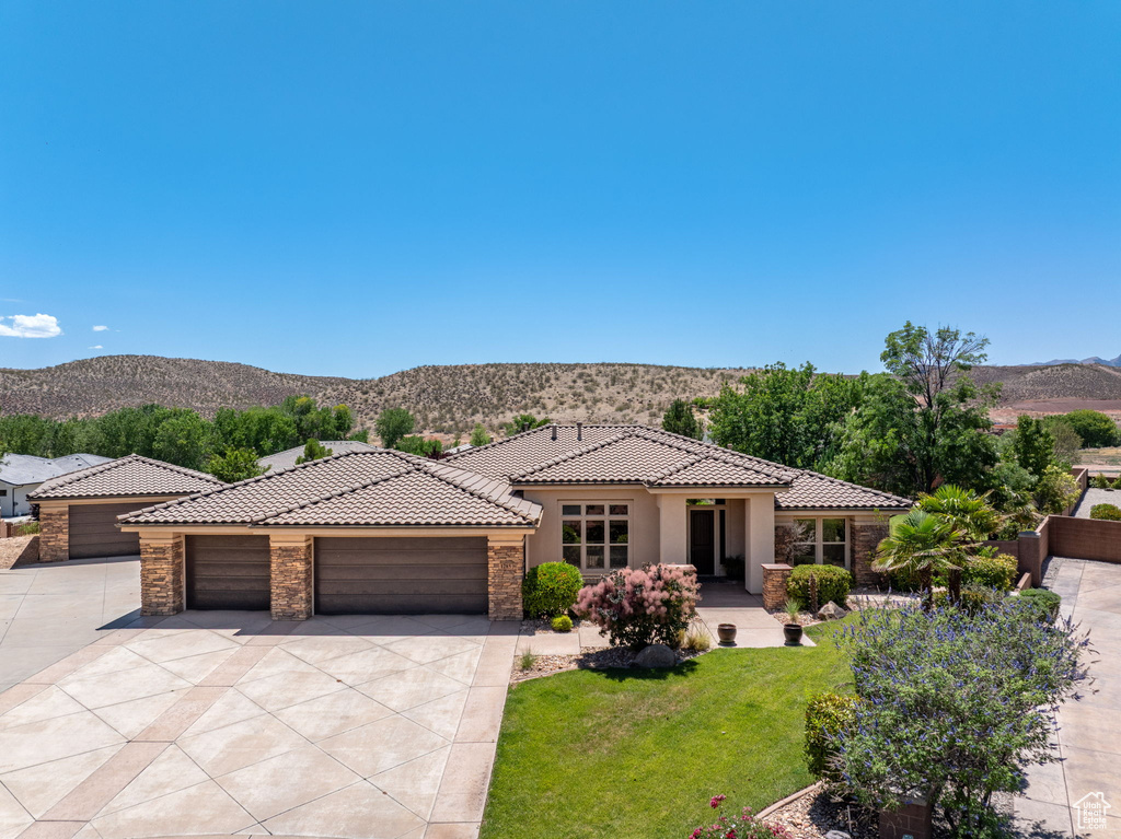 Mediterranean / spanish house featuring a mountain view, stone siding, a tiled roof, concrete driveway, and a garage