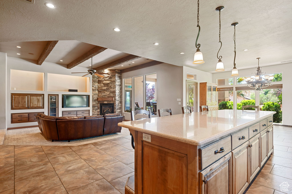 Kitchen with plenty of natural light, a stone fireplace, recessed lighting, a ceiling fan, and a textured ceiling