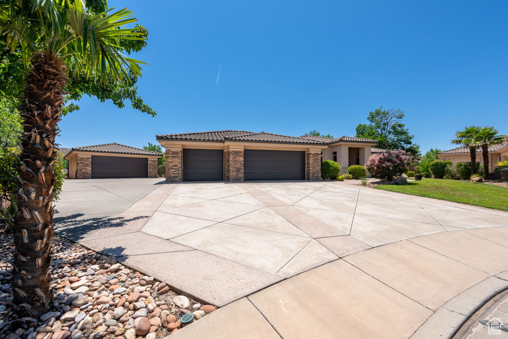 View of front of home featuring concrete driveway, a tiled roof, a garage, stucco siding, and a front yard