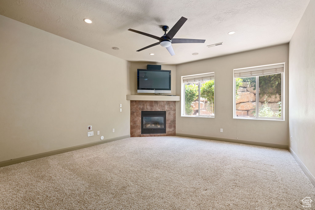 Unfurnished living room with carpet flooring, a fireplace, a textured ceiling, a ceiling fan, and recessed lighting