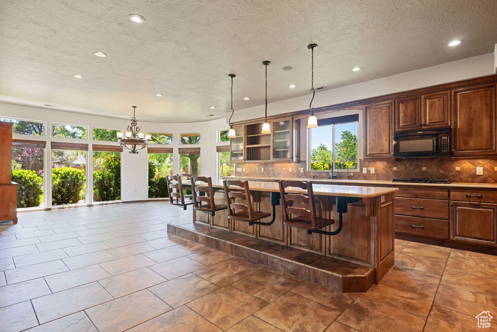 Kitchen featuring black microwave, recessed lighting, gas cooktop, decorative backsplash, and light countertops