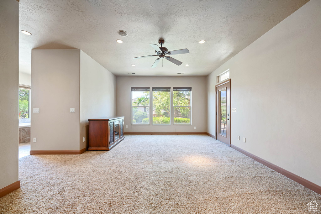 Empty room featuring light colored carpet, healthy amount of natural light, a ceiling fan, a textured ceiling, and recessed lighting