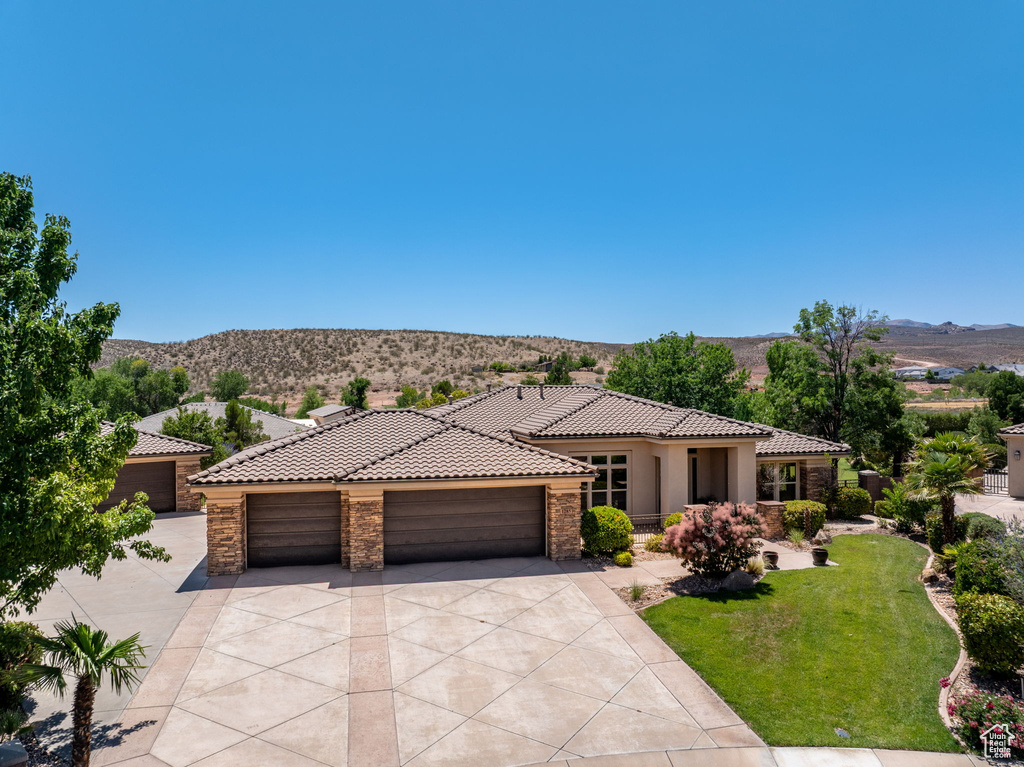 Mediterranean / spanish-style house featuring stone siding, a tile roof, and a mountain view