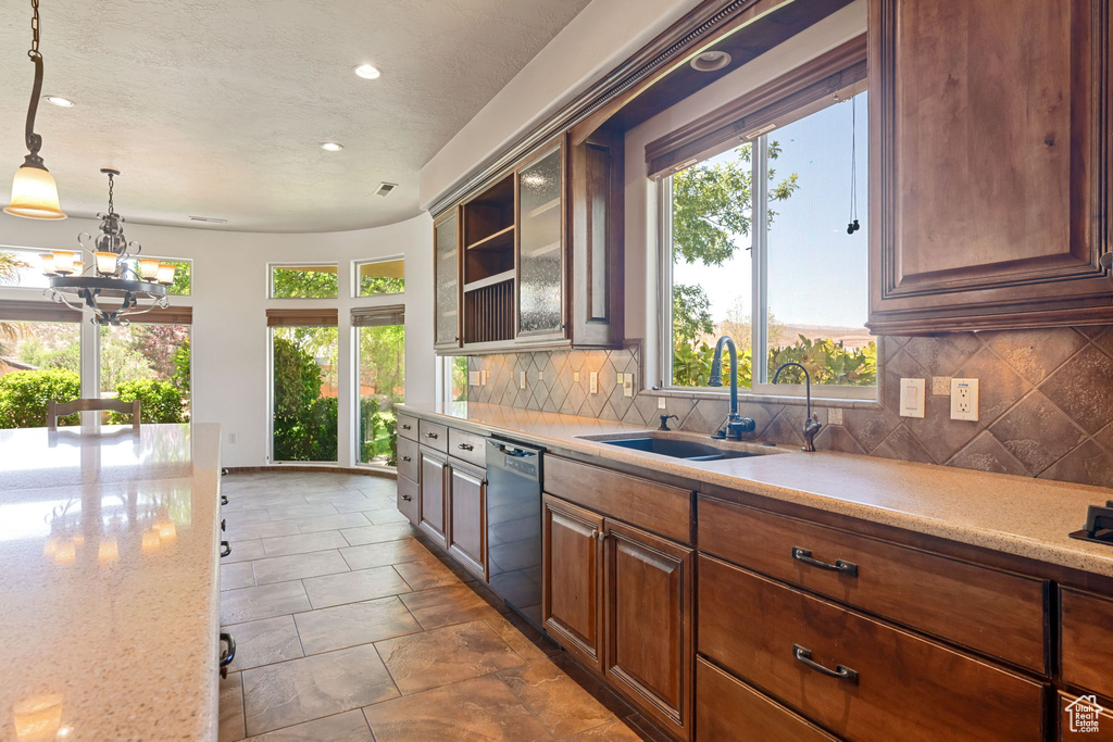 Kitchen featuring dishwashing machine, recessed lighting, decorative backsplash, a chandelier, and pendant lighting