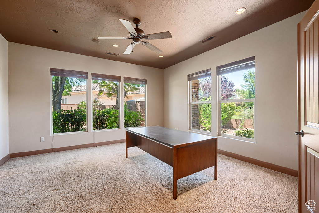 Office area featuring plenty of natural light, light carpet, a textured ceiling, a ceiling fan, and recessed lighting