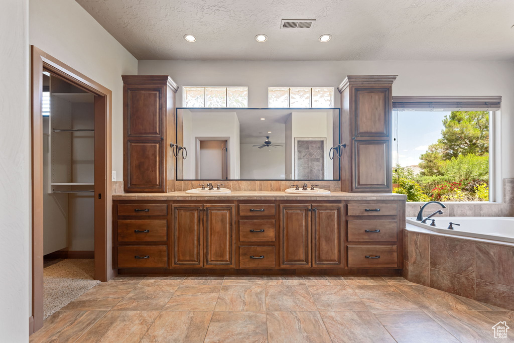 Full bathroom with double vanity, a garden tub, a textured ceiling, a ceiling fan, and recessed lighting