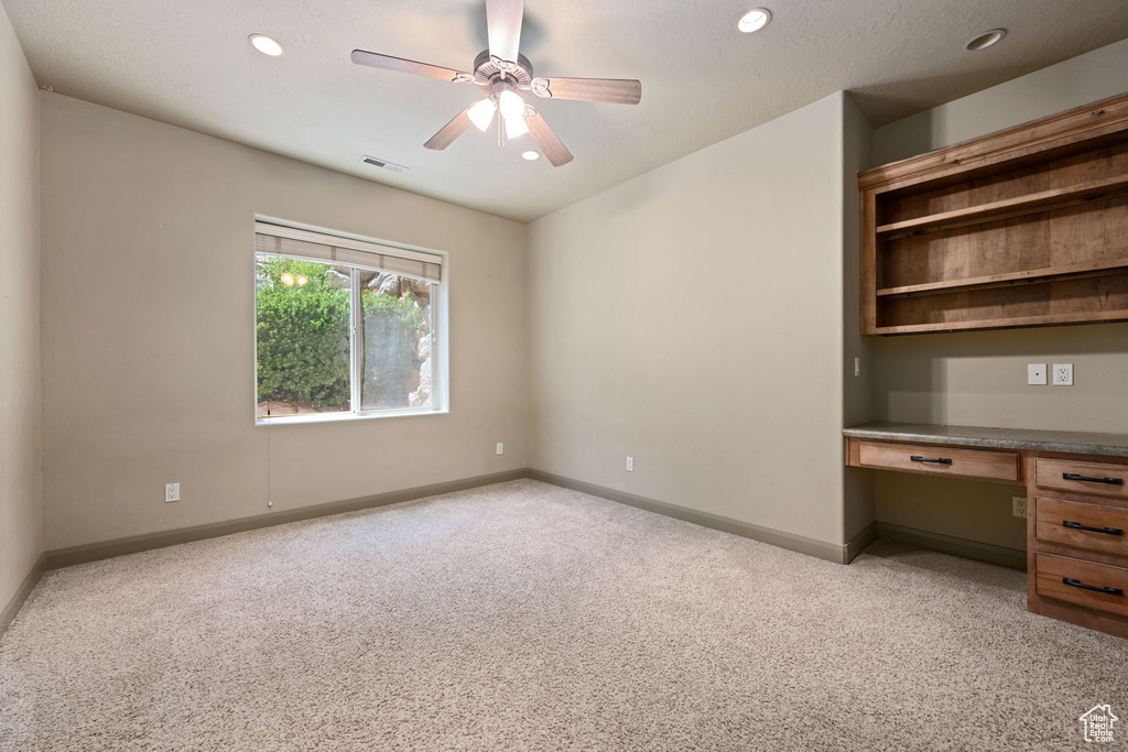 Unfurnished office with built in study area, light carpet, recessed lighting, and a ceiling fan