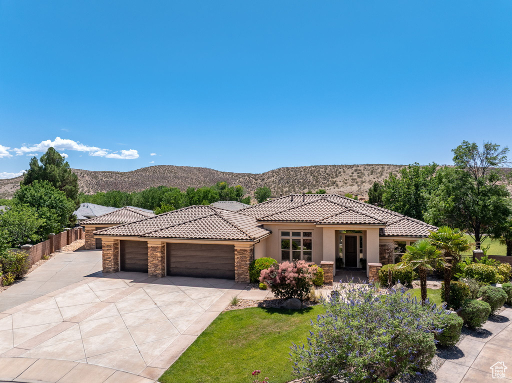 View of front facade featuring stone siding, a tiled roof, a garage, and stucco siding