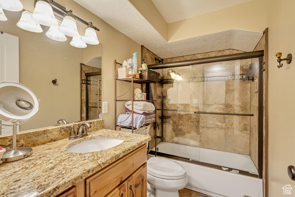 Bathroom with vanity and bath / shower combo with glass door