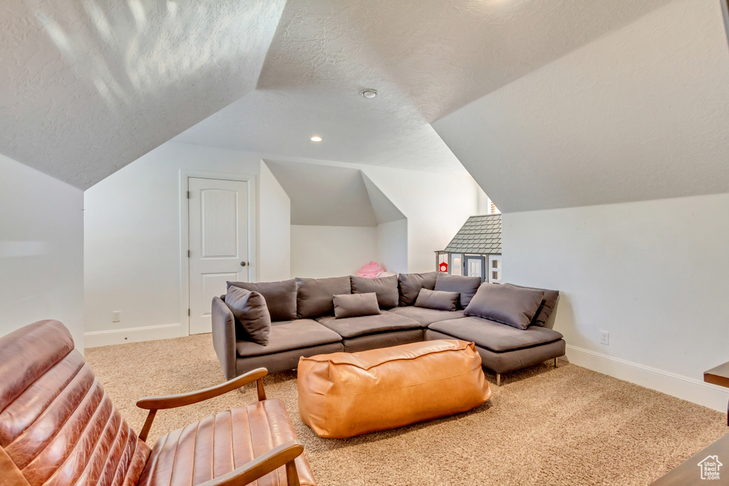 Carpeted home theater room with a textured ceiling, vaulted ceiling, and recessed lighting