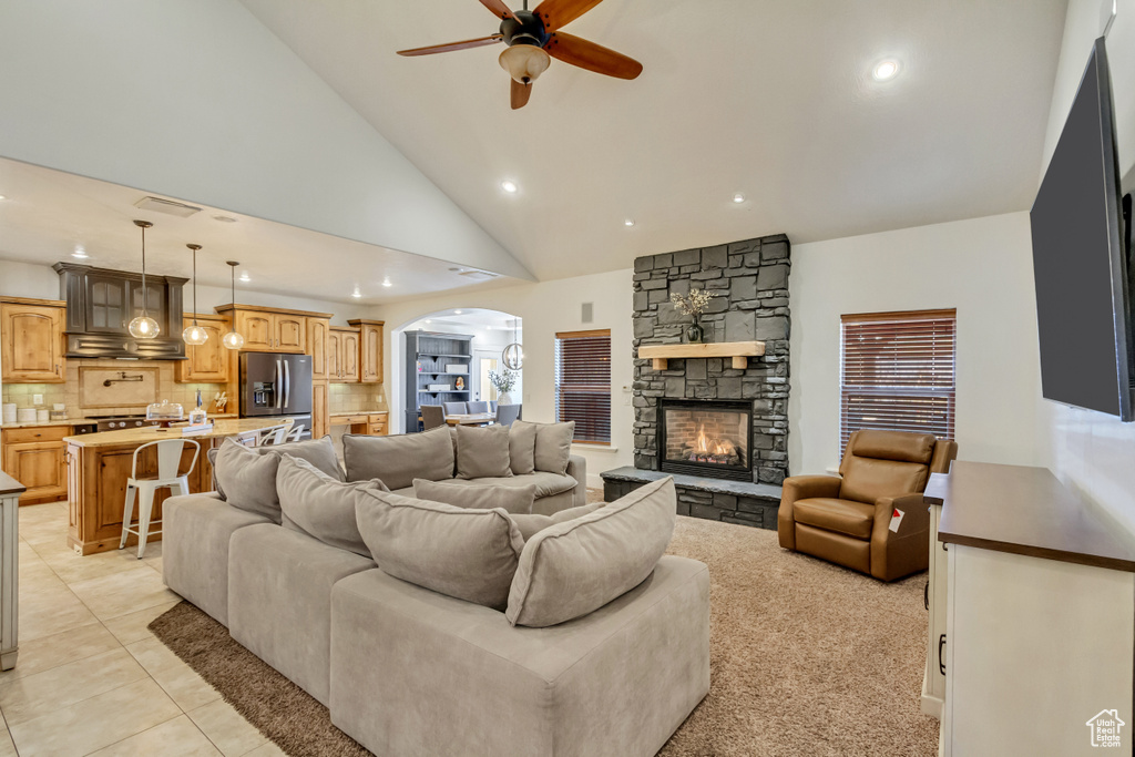 Living area featuring ceiling fan, arched walkways, recessed lighting, a fireplace, and light tile patterned flooring