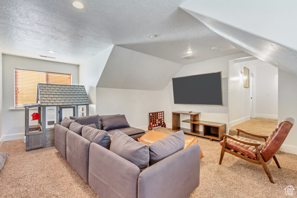 Carpeted cinema room with a textured ceiling, recessed lighting, and vaulted ceiling