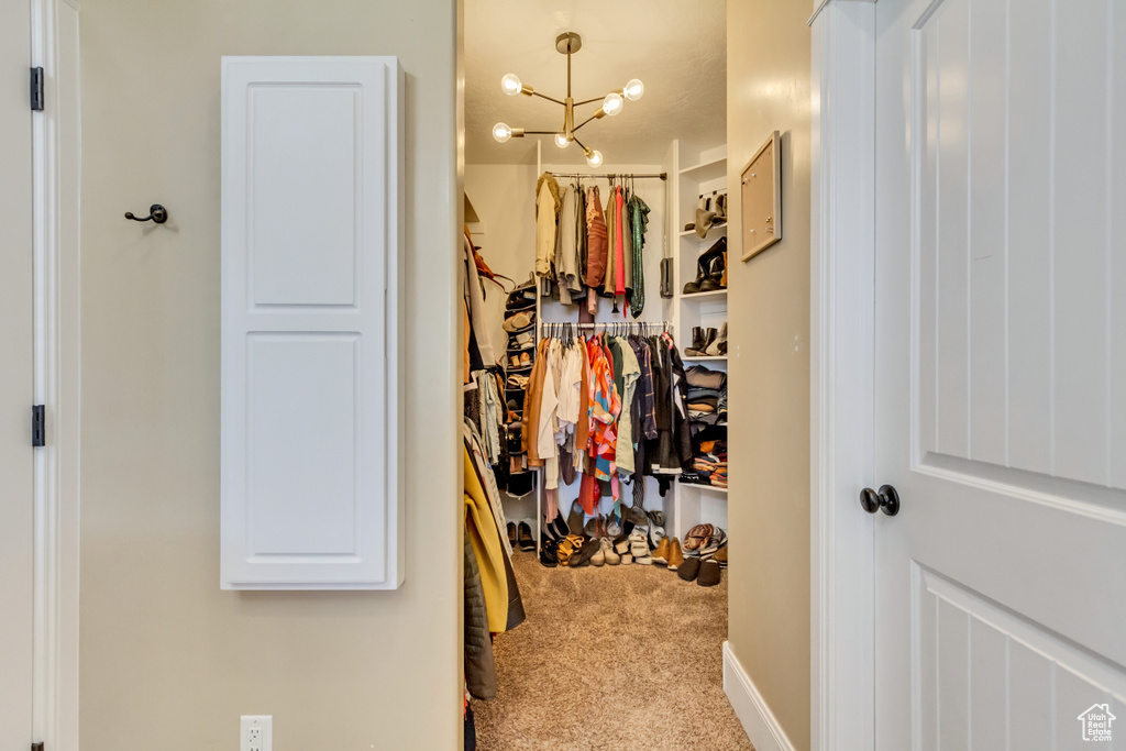 Walk in closet with carpet flooring and a chandelier