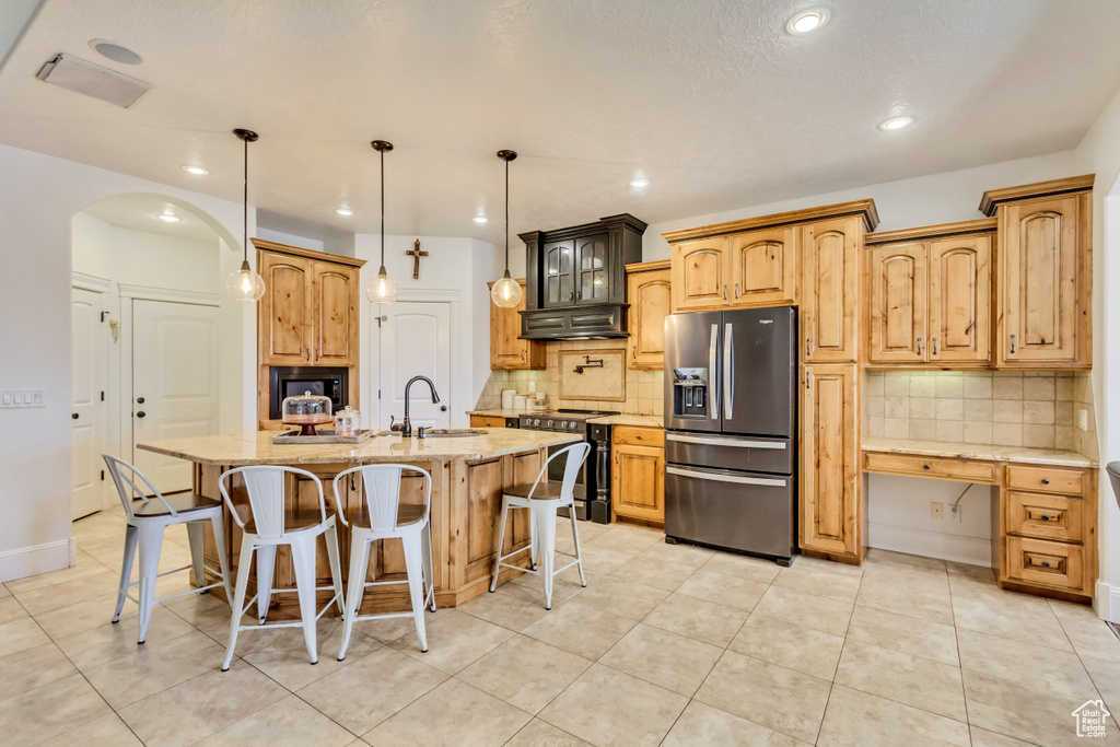 Kitchen with appliances with stainless steel finishes, under cabinet range hood, decorative backsplash, light stone counters, and recessed lighting
