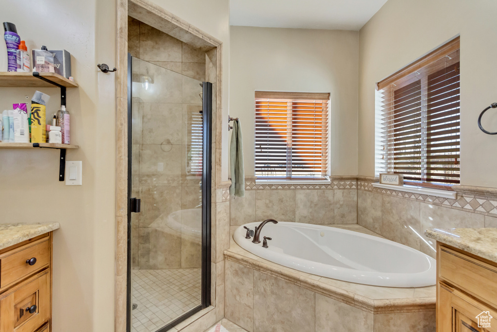 Full bathroom featuring vanity, a garden tub, and a shower stall