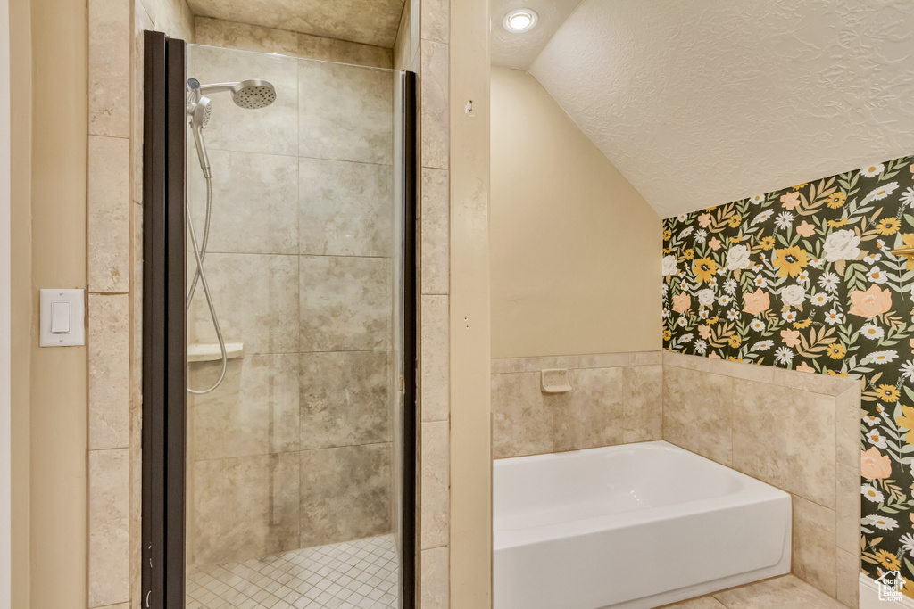 Full bath with wallpapered walls, a garden tub, lofted ceiling, a shower stall, and a textured ceiling