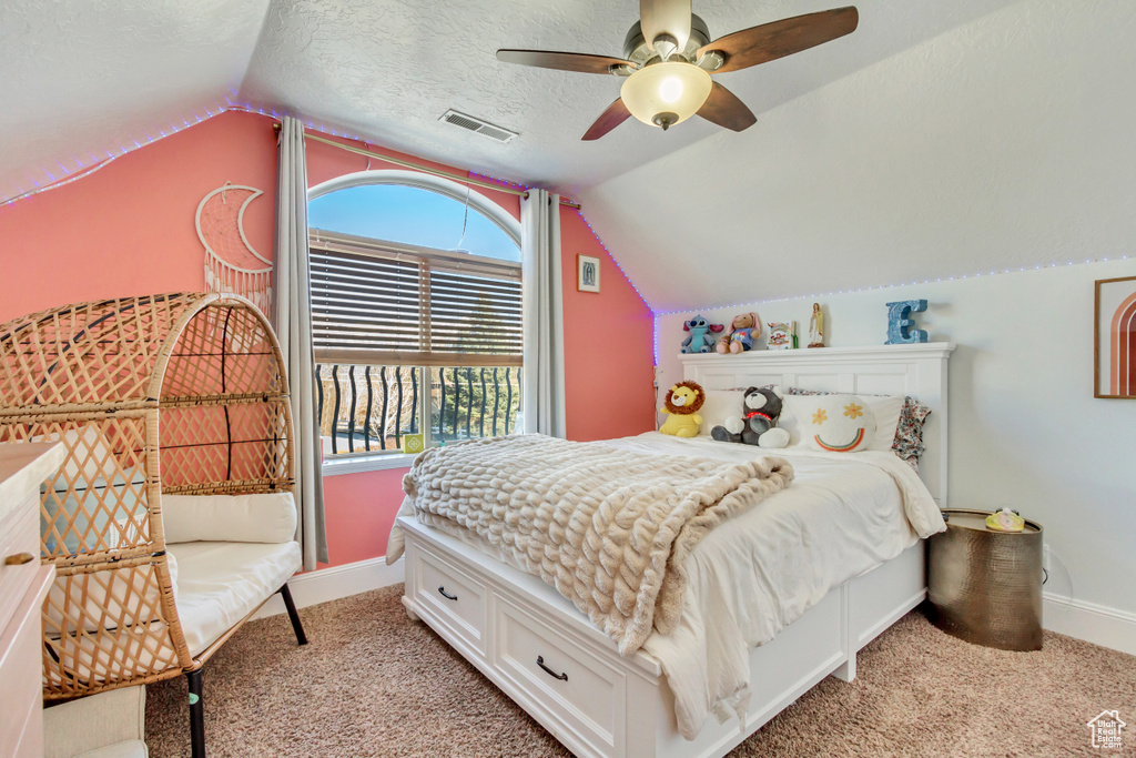 Bedroom with lofted ceiling, light carpet, multiple windows, a textured ceiling, and ceiling fan