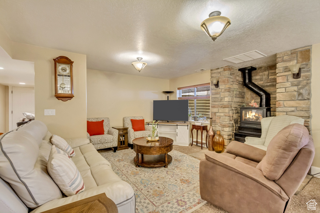 Living area featuring a wood stove, light colored carpet, and a textured ceiling