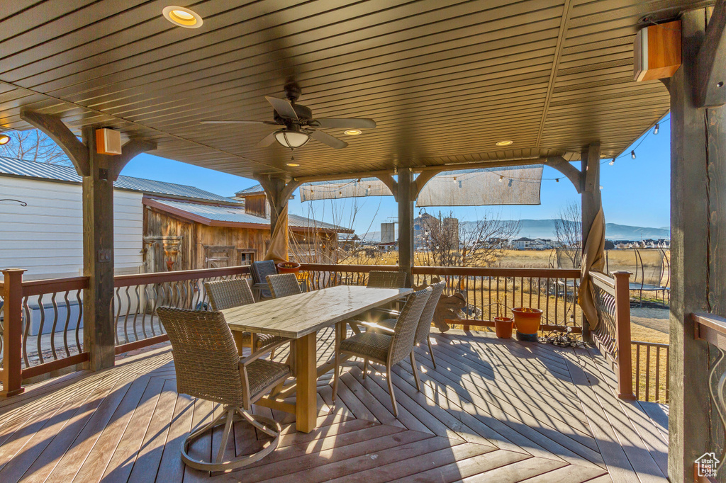 Wooden terrace featuring outdoor dining area and ceiling fan