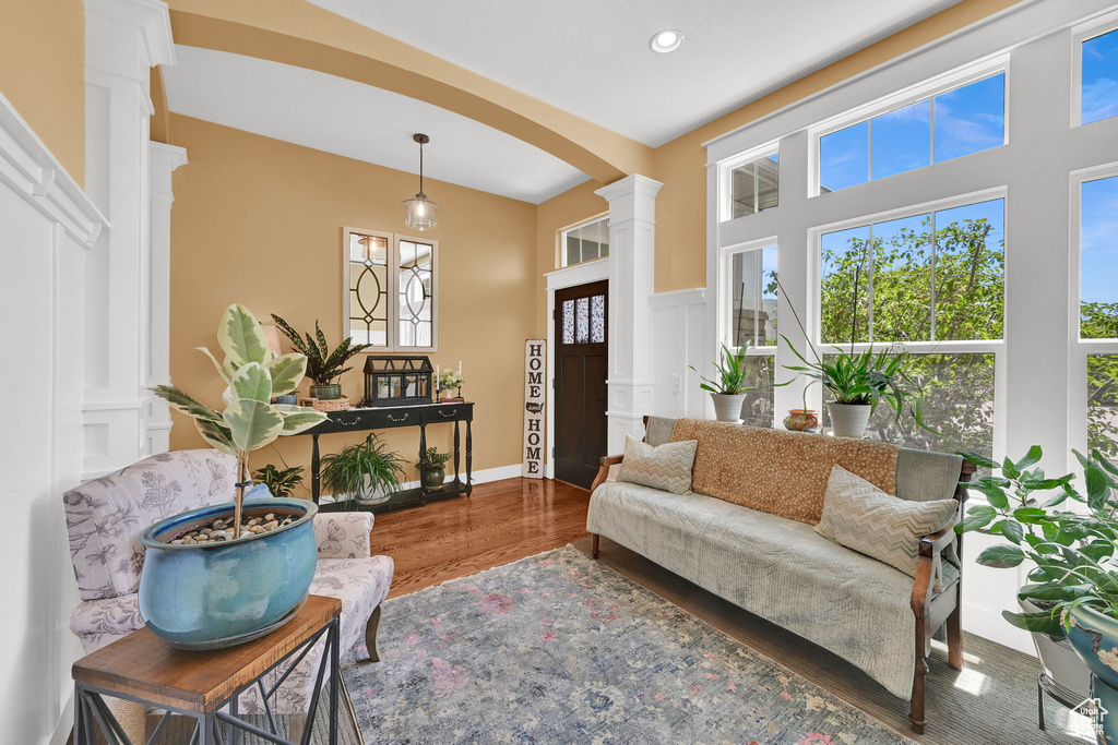 Living room with decorative columns, wood finished floors, arched walkways, and recessed lighting