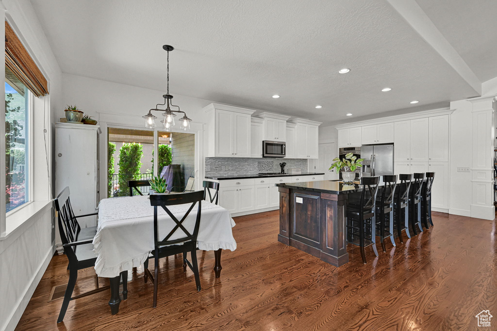 Kitchen with appliances with stainless steel finishes, dark countertops, healthy amount of natural light, decorative backsplash, and recessed lighting