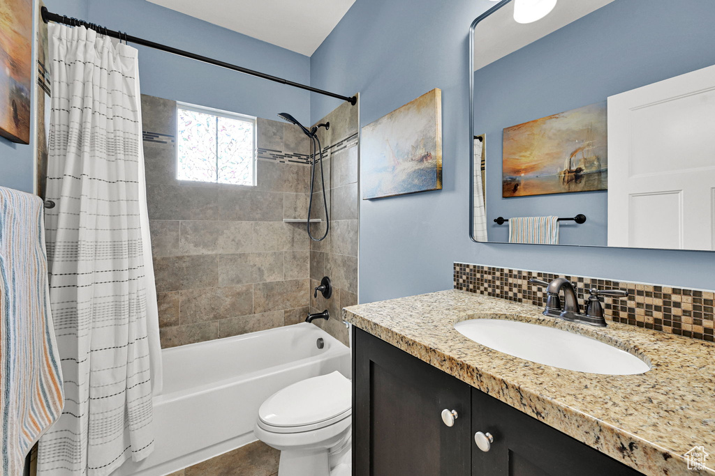 Full bath with shower / tub combo with curtain, vanity, and tasteful backsplash