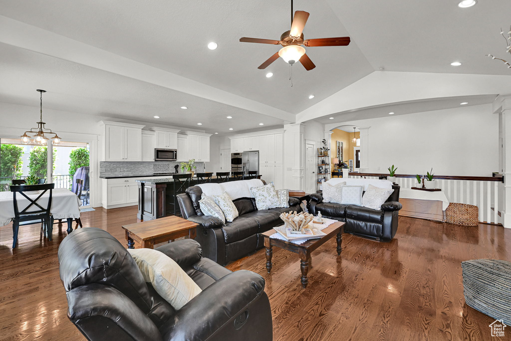 Living area featuring a ceiling fan, ornate columns, lofted ceiling, dark wood finished floors, and arched walkways
