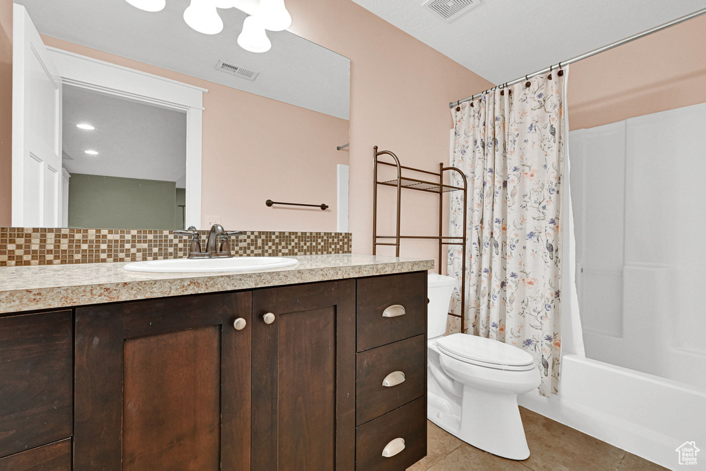 Bathroom featuring tasteful backsplash, vanity, tile patterned floors, and shower / bath combo