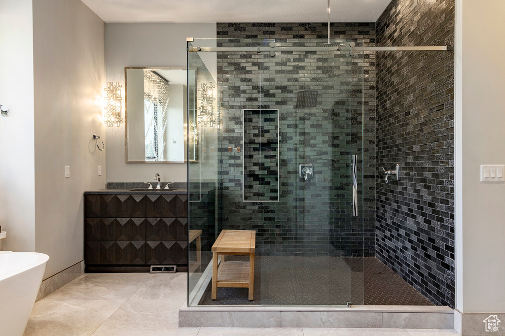 Full bathroom with a shower stall, vanity, tile patterned floors, and a freestanding tub