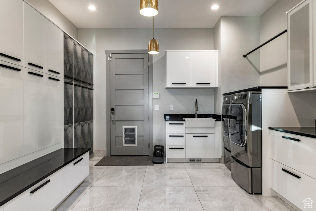 Laundry room with cabinet space, washing machine and clothes dryer, recessed lighting, and light marble finish floors