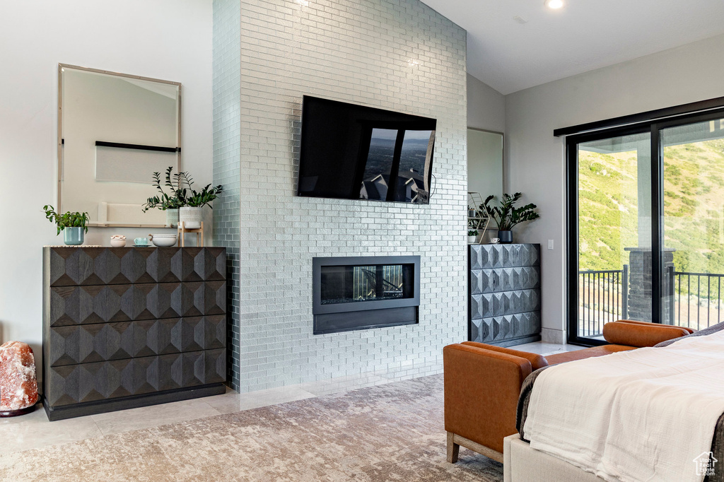 Bedroom with a fireplace, access to outside, lofted ceiling, and tile patterned flooring
