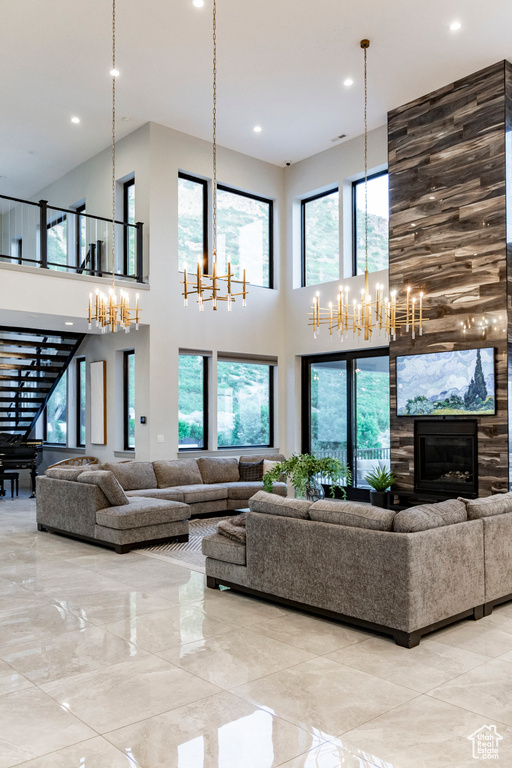 Living area featuring a chandelier, a high ceiling, recessed lighting, and a large fireplace