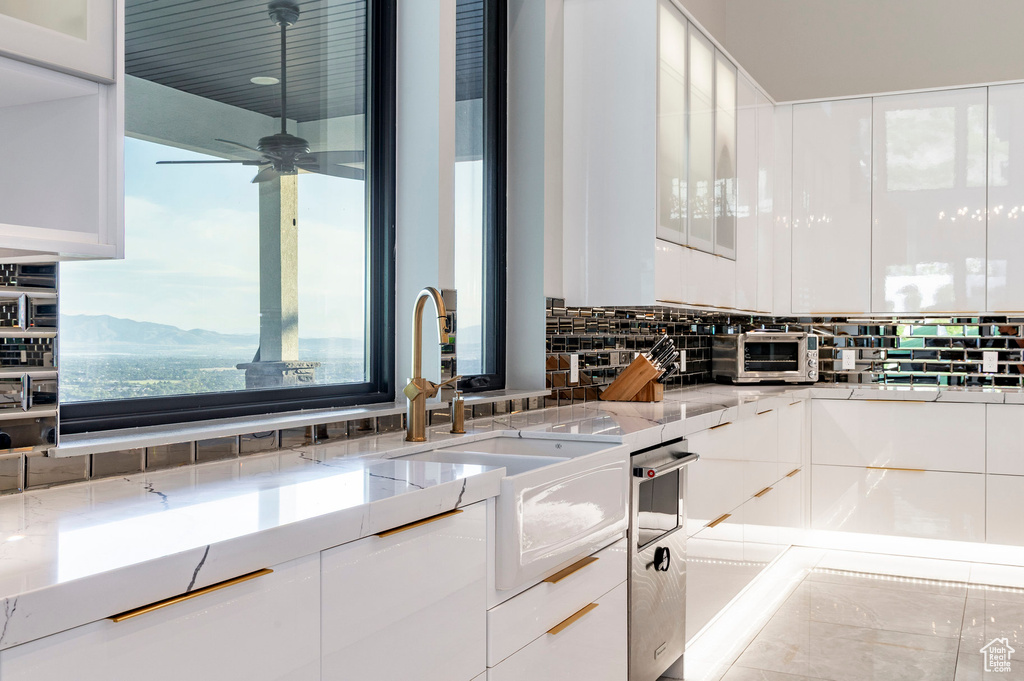 Kitchen with white cabinets, backsplash, modern cabinets, and ceiling fan