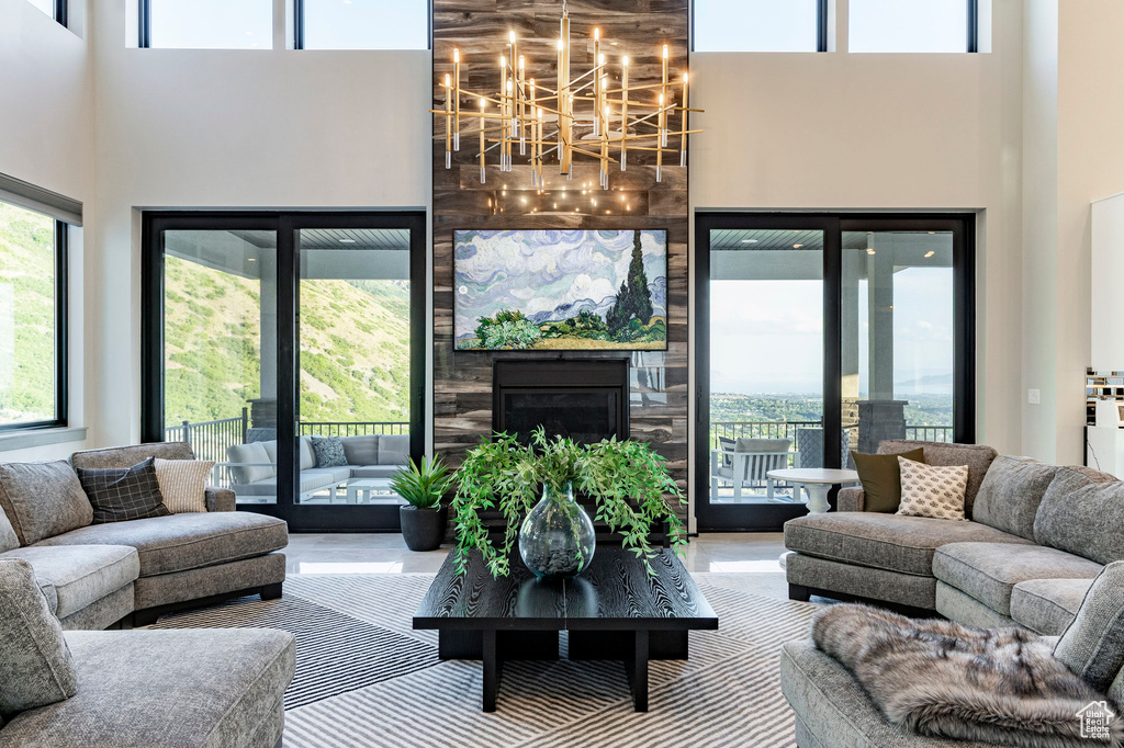Living room with a high ceiling, wood finished floors, a chandelier, and a large fireplace
