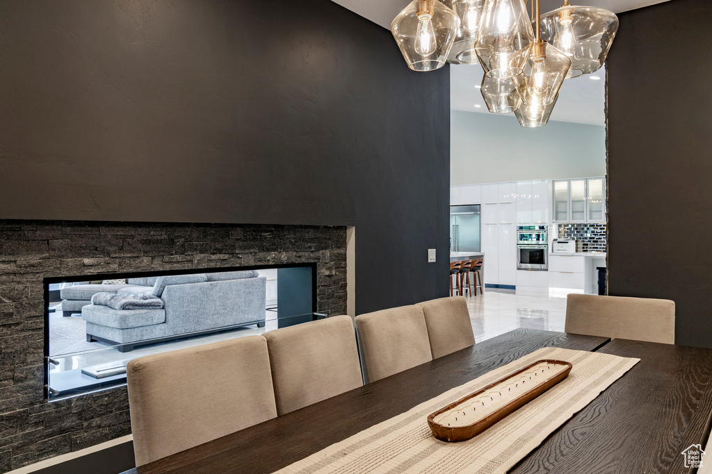 Dining space featuring a chandelier, high vaulted ceiling, and a stone fireplace