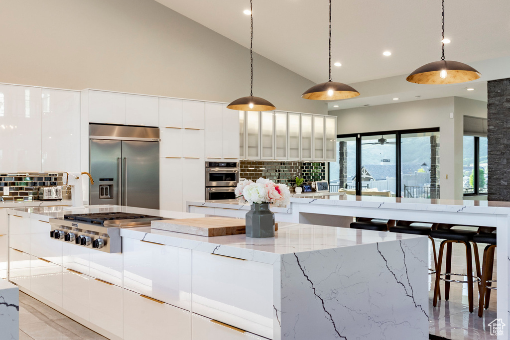 Kitchen with appliances with stainless steel finishes, modern cabinets, a large island, white cabinetry, and backsplash