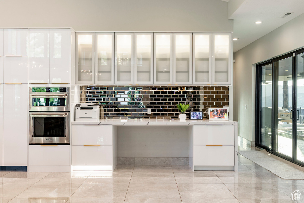Kitchen with double oven, white cabinetry, modern cabinets, decorative backsplash, and recessed lighting