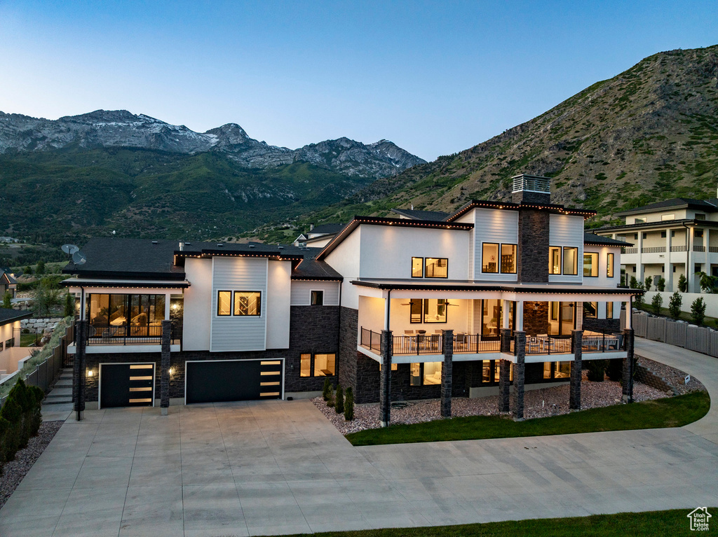 Rear view of house featuring stone siding, a garage, a balcony, and a mountain view