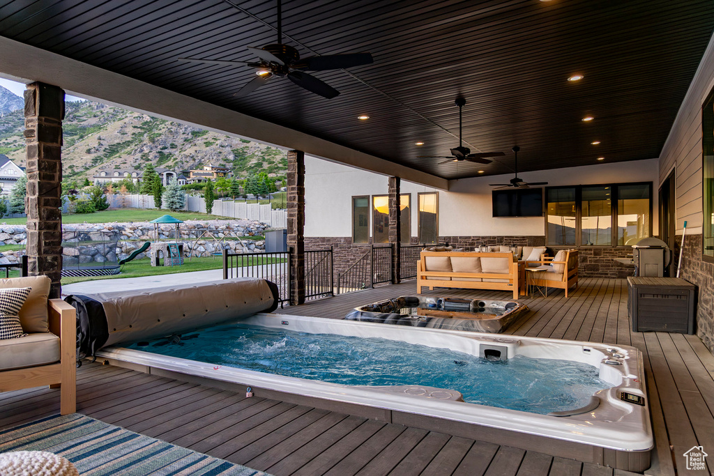 Wooden terrace featuring a ceiling fan, an outdoor living space, and a mountain view