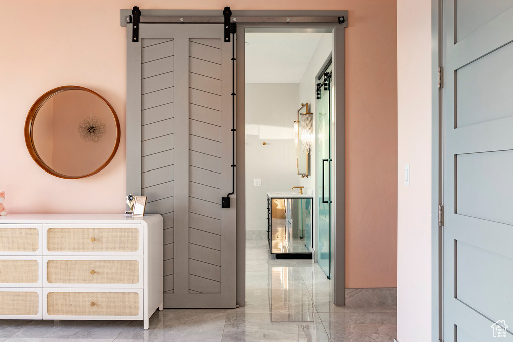 Hall featuring light marble finish flooring and a barn door