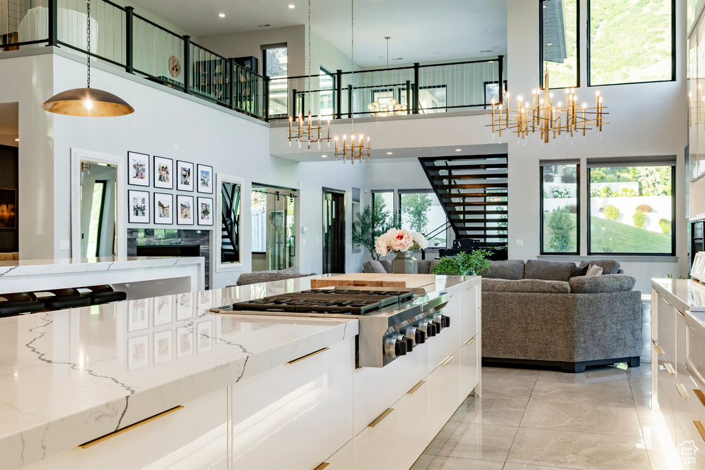 Kitchen featuring a chandelier, open floor plan, a high ceiling, white cabinets, and plenty of natural light