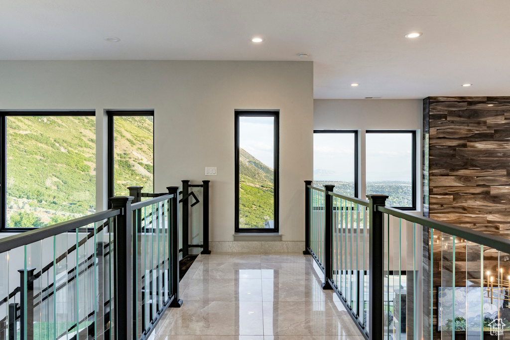 Hall featuring recessed lighting, light marble finish flooring, and an upstairs landing