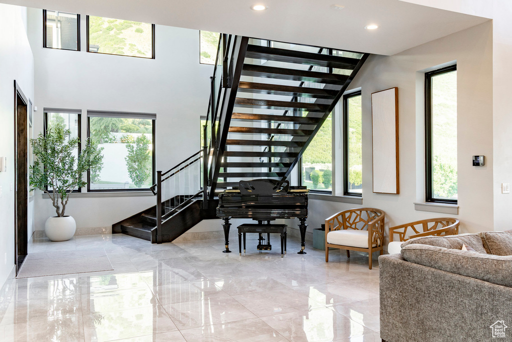 Staircase with marble tiled floors, a towering ceiling, and recessed lighting