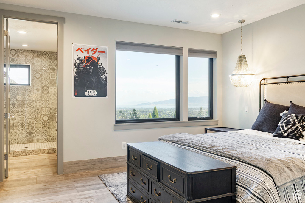 Bedroom featuring light wood-style floors, multiple windows, recessed lighting, and ensuite bath