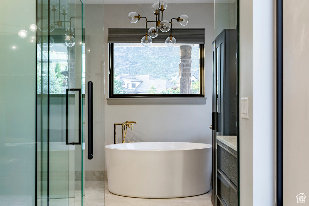 Full bathroom featuring a stall shower, a freestanding tub, a chandelier, and vanity