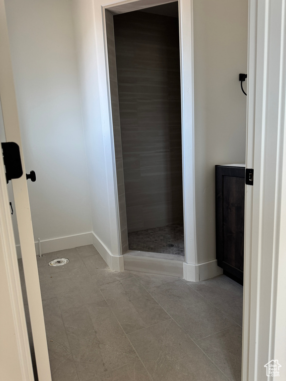 Bathroom featuring tile patterned flooring, baseboards, and tiled shower