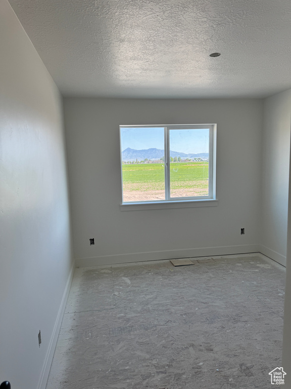 Empty room with a textured ceiling and baseboards