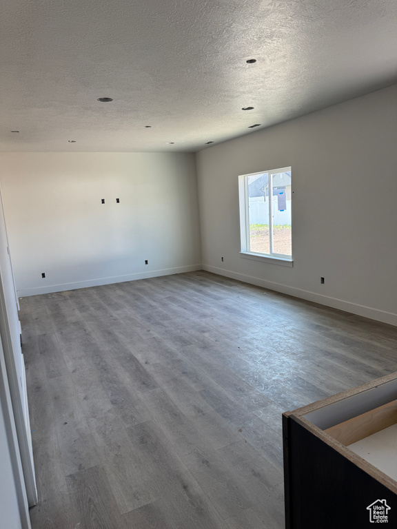 Empty room with wood finished floors, a textured ceiling, and baseboards