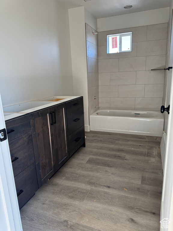 Bathroom with vanity, wood finished floors, and shower / washtub combination