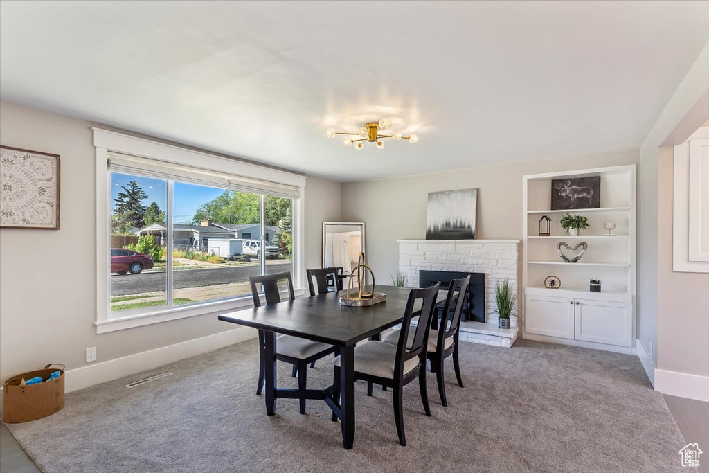 Dining room featuring a fireplace, a chandelier, and carpet